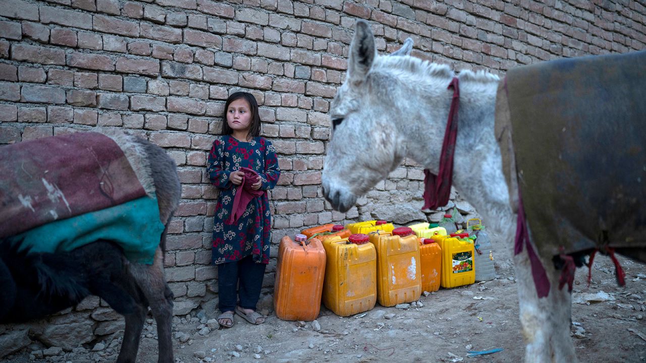 An Afghan girl stands next canisters as she waits to fill them up with water in Kabul, Afghanistan, November 13, 2021.