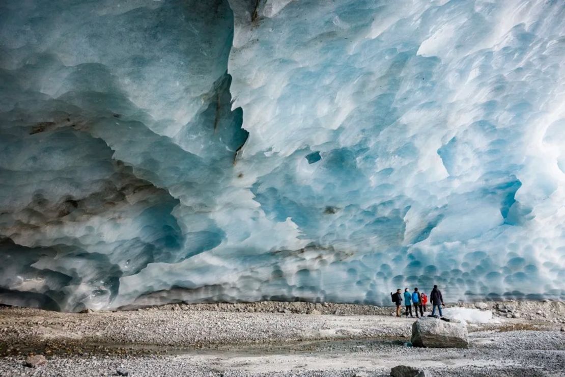 Excursionistas visitan una cueva de hielo formada en la sección final del glaciar Zinal en Suiza.