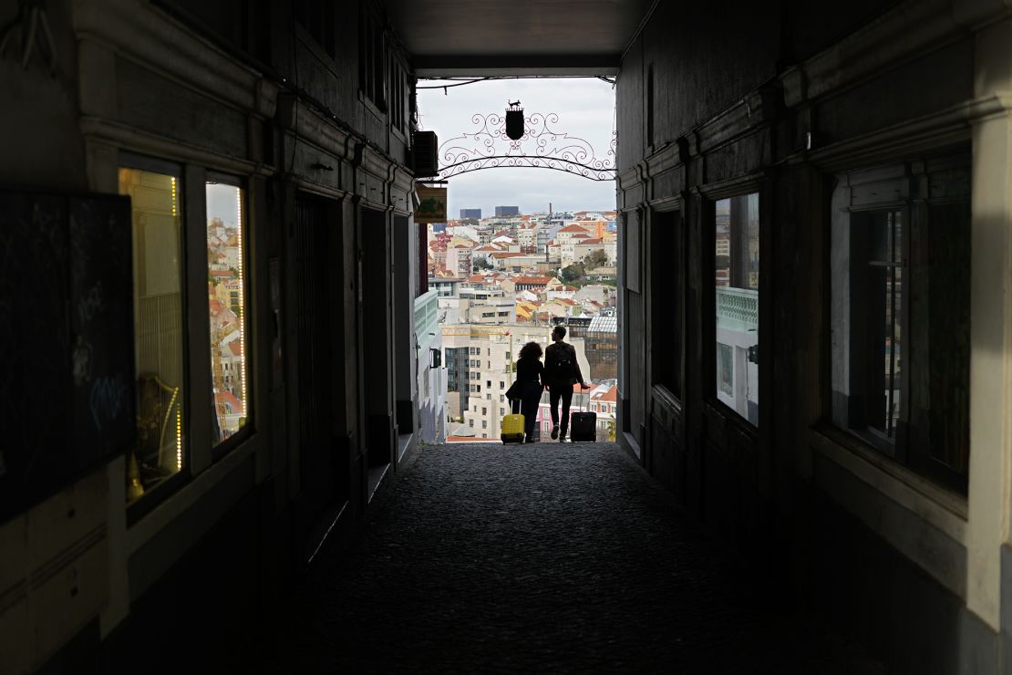 A couple pull suitcases along an alley in Lisbon, Portugal.