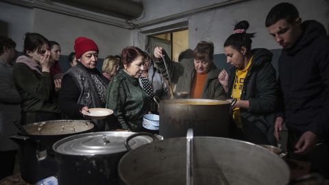 People queue to receive hot food in the improvised bomb shelter in Mariupol.