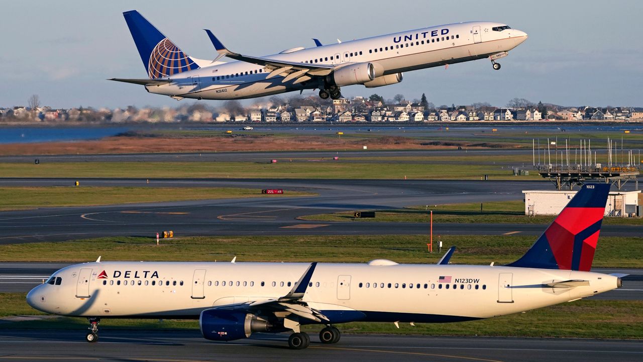 A United Airlines jet takes off while a Delta Airlines plane taxis at Logan International Airport, Monday, Nov. 21, 2022, in Boston. Travel experts say the ability of many people to work remotely is letting them take off early for Thanksgiving or return home later. Crowds are expected to rival those of 2019, the last Thanksgiving before the pandemic. (AP Photo/Charles Krupa)