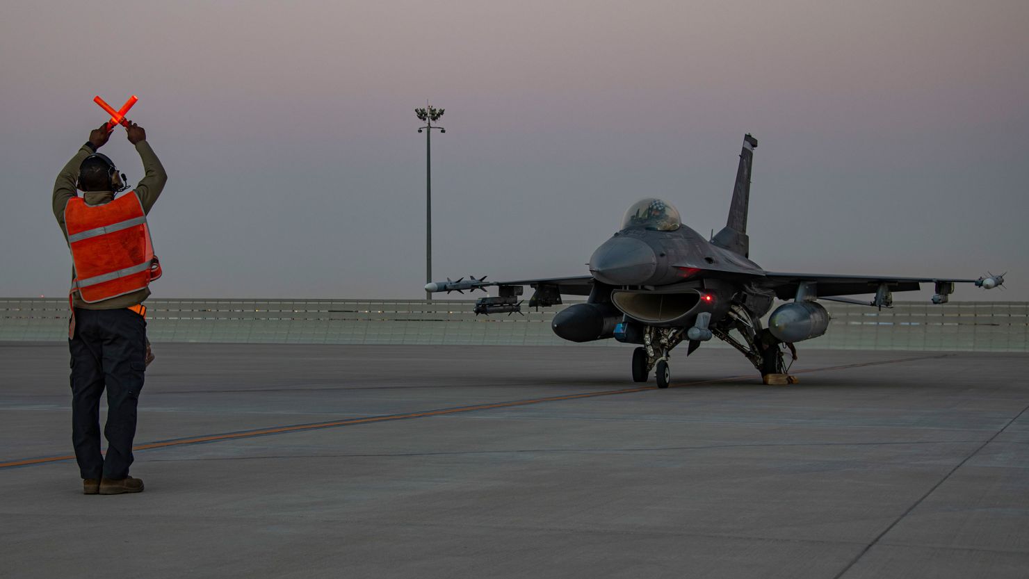 In this handout photo from the US Air Force, an airman guides an F-16 Fighting Falcon during training at Al-Udeid Air Base, Qatar, Jan. 24, 2022. 