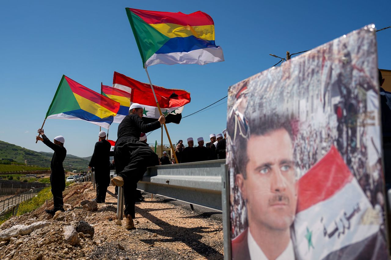 Druze men carry Syrian flags and a picture of Syrian President Bashar Assad during a rally marking Syria's Independence Day, in a Druze village in the Israeli-controlled Golan Heights, on the border with Syria, in 2023.