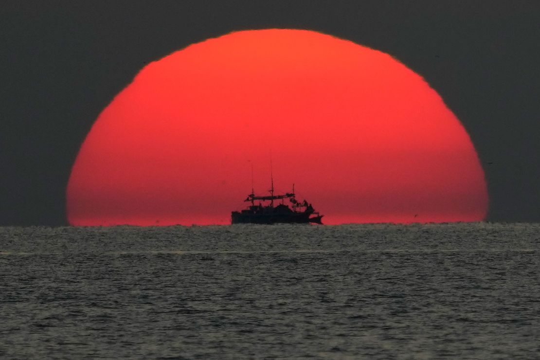 A fishing boat passes by a setting sun in the Sulu Sea.