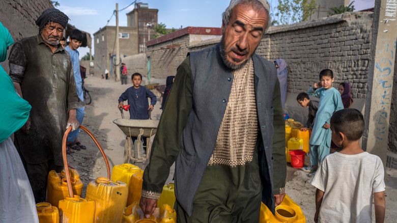 Neighbors gather to fill their drums with drinking water in Azara neighborhood in Kabul on June 14, 2023.
