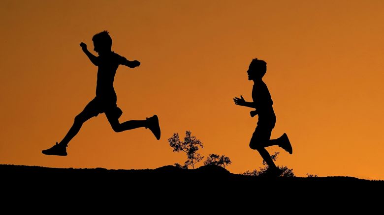 FILE - Boys are silhouetted against the sky at sunset as they run along a ridge at Papago Park, April 1, 2022, in Phoenix. President Joe Biden plans to announce new steps to address the extreme heat that has threatened millions of Americans, most recently in the Southwest.