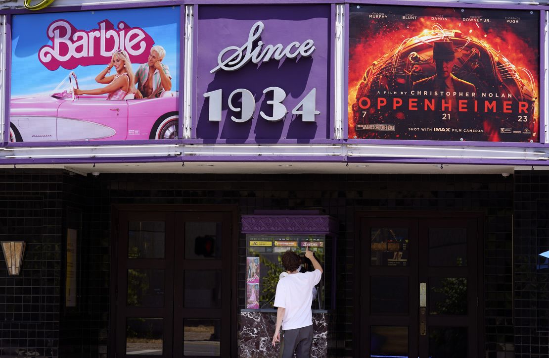 A patron buys a movie ticket underneath a marquee featuring the films 