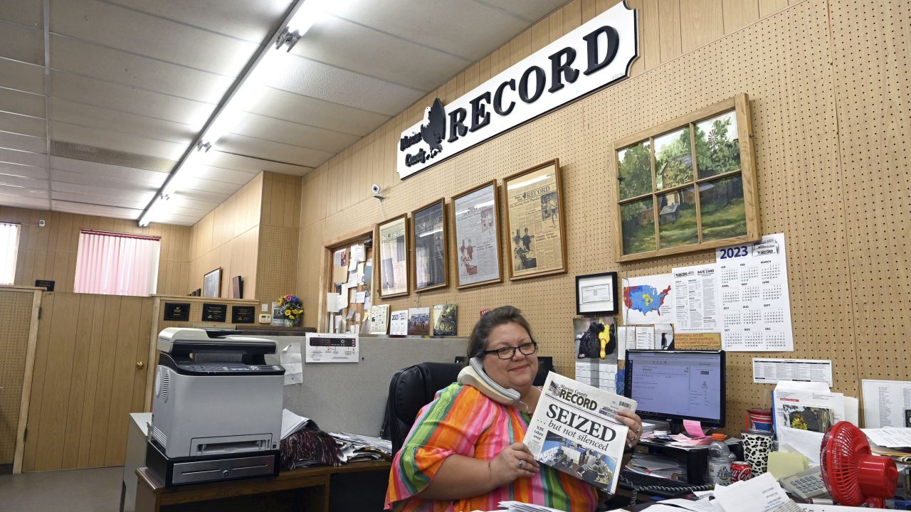 Cheri Bentz. a staffer at the paper, sits at her desk answering the phone. on August 17, 2023, with copies of the edition of the paper that came out after the raid.