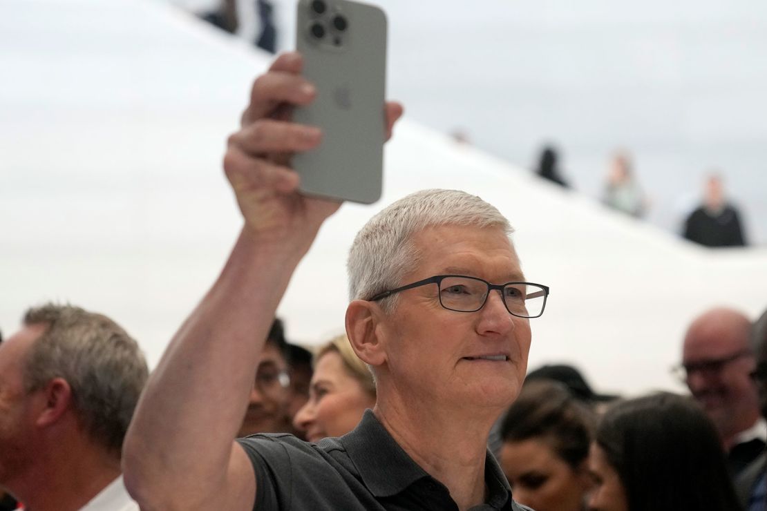 Apple CEO Tim Cook holds an iPhone 15 Pro on the company's campus in September 2023. Cook has been working to build rapport with Donald Trump during the president's second term.