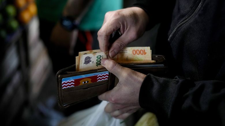 A shopper reaches for a 1,000 pesos banknote, in Buenos Aires, Argentina, Sept. 1, 2023.