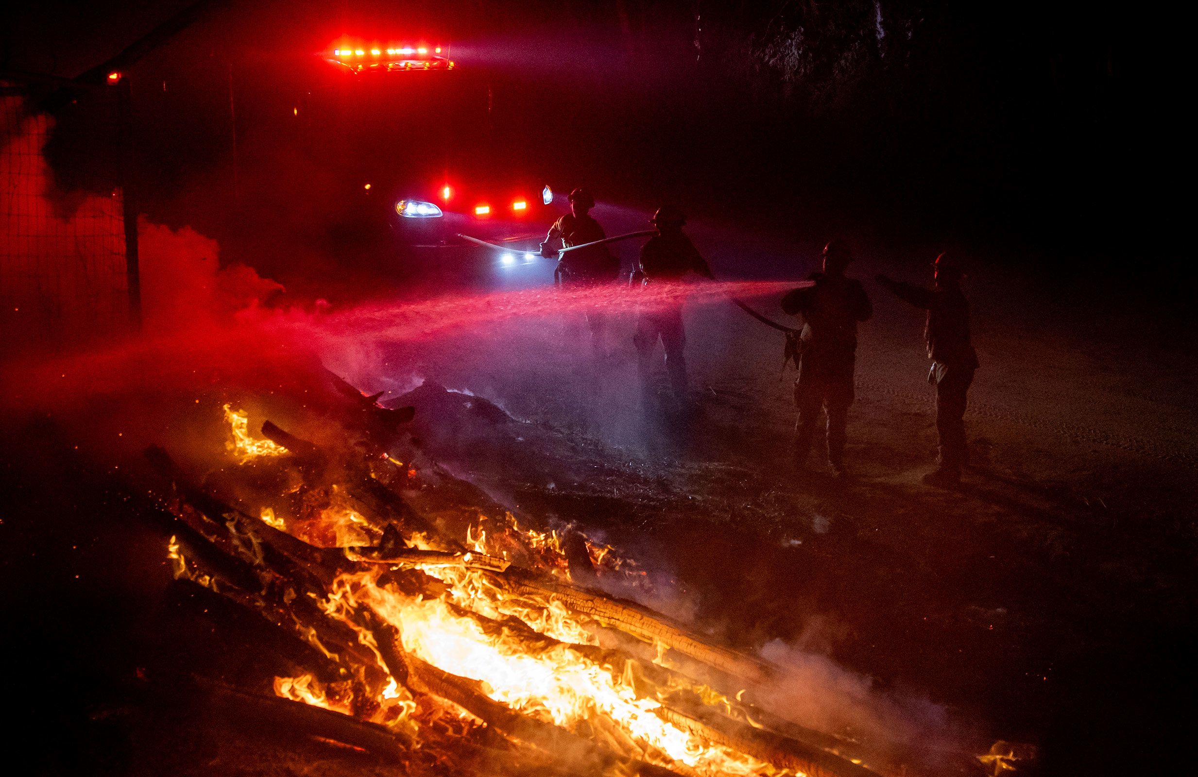 Firefighters douse flames while battling a wildfire called the Highland Fire in Aguanga, California, on Monday, October 30.