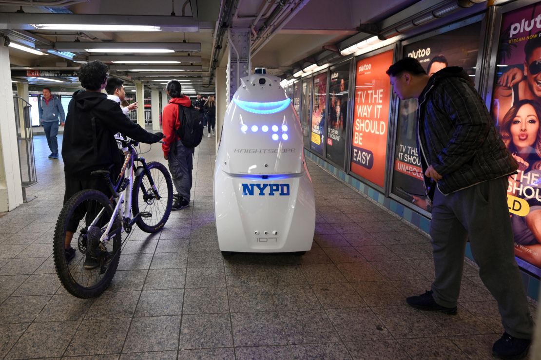 Commuters pause to look at the NYPD's Knightscope K5 autonomous security robot at the Times Square subway station in New York City.