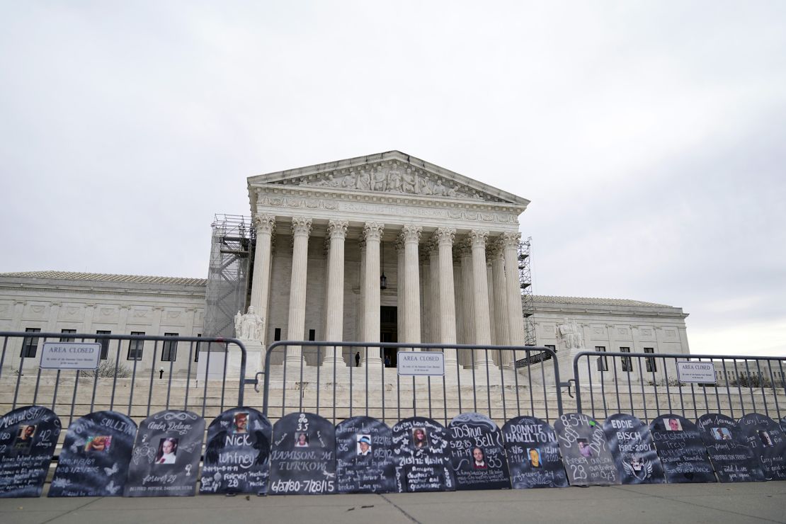 Signs in the shape of grave headstones, with information on people who died from using OxyContin, line a security fence outside the Supreme Court Monday, Dec. 4, 2023, in Washington, DC.