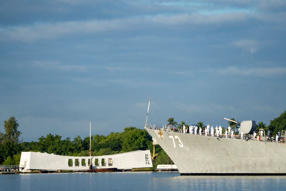 Sailors aboard the the USS Decatur render honors while passing the USS Arizona Memorial and the sunken battleship the USS Arizona during the 82nd Pearl Harbor Remembrance Day ceremony on Thursday, December 7, 2023, at Pearl Harbor in Honolulu, Hawaii.