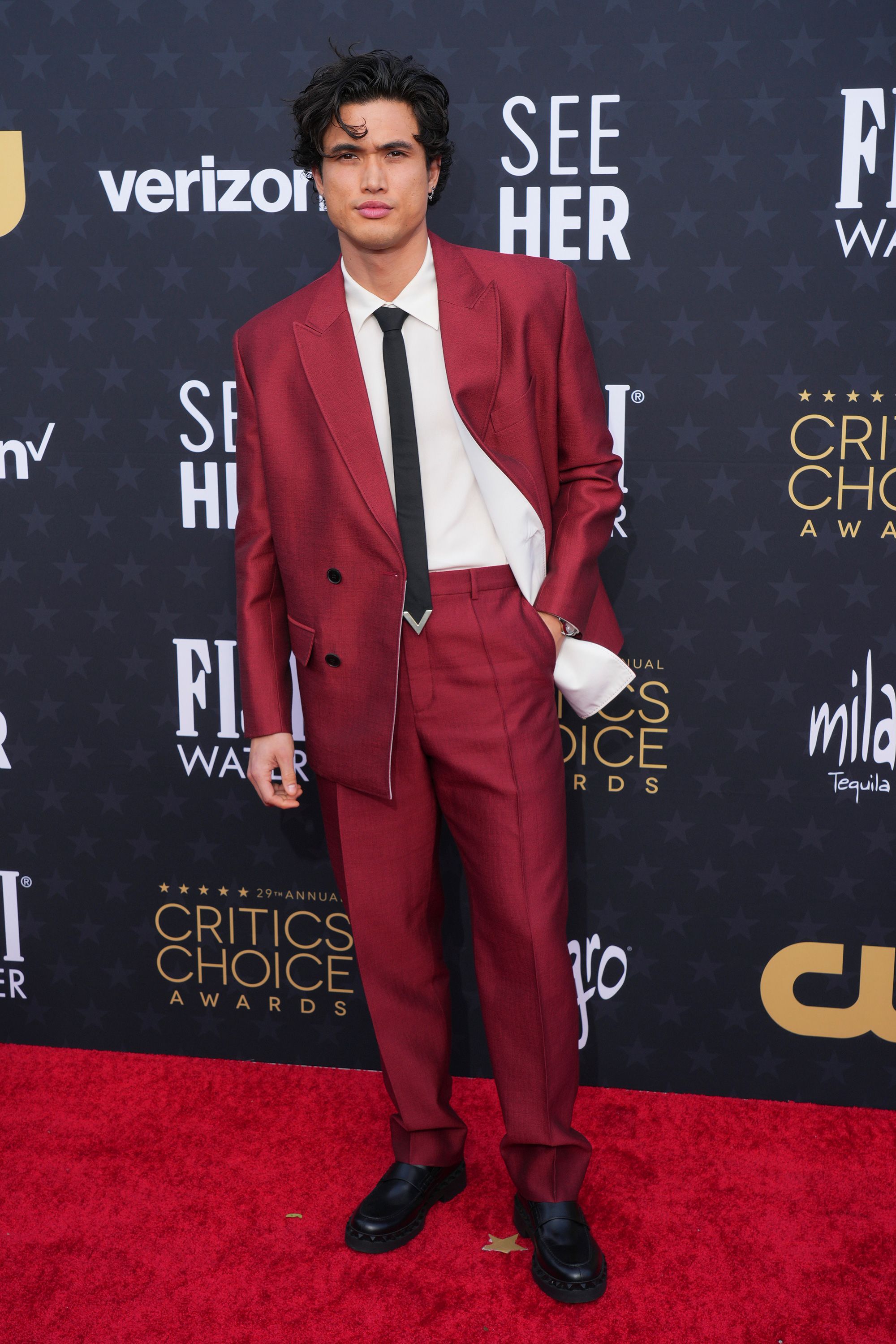 Charles Melton, nominated in the best supporting actor for his performance in "May December," wore a red Valentino suit paired with a black skinny tie featuring a V-shaped metallic accent.