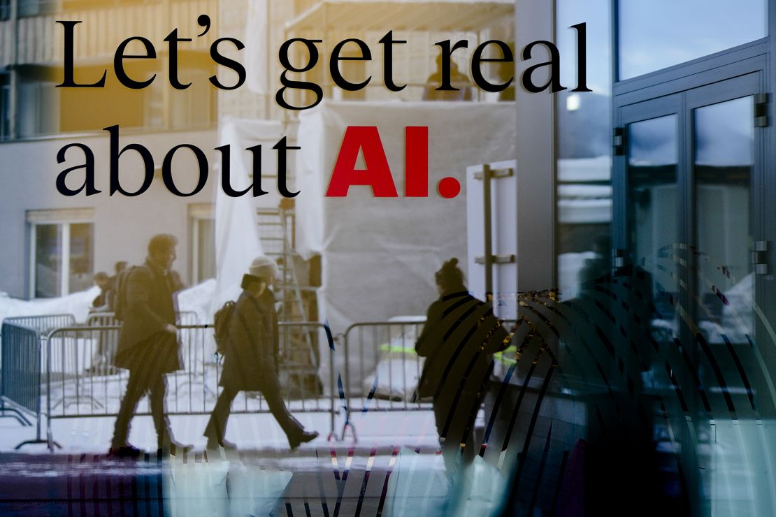 People reflected in a window of a hotel In Davos, Switzerland with a slogan about AI, as the World Economic Forum begins its annual meeting in the ski resort.