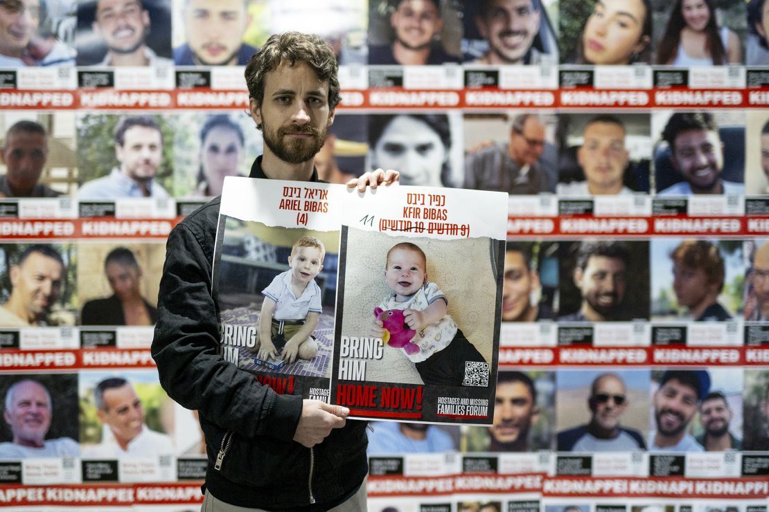 A relative of Ariel and Kfir Bibas holds their photos in Tel Aviv in January 2024.