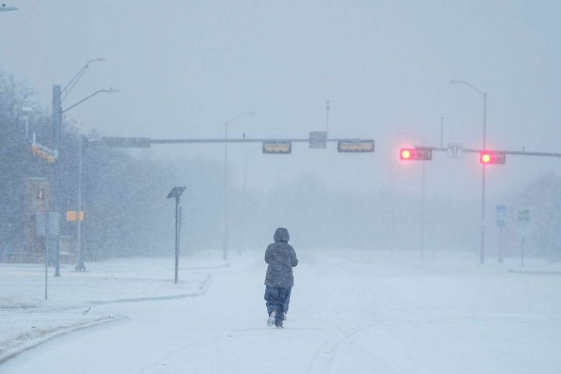 A jogger trots on a snow-covered road during a winter storm, Monday, Jan. 15, 2024, in Grand Prairie, Texas.