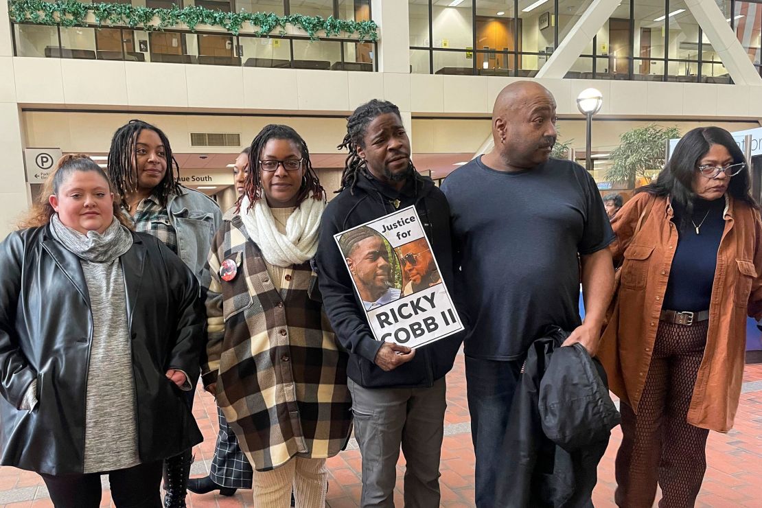 Family and activists for Ricky Cobb II stand with a sign saying 