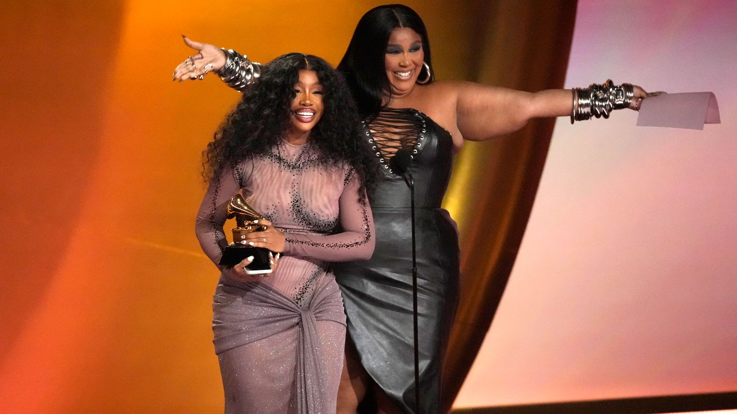 Lizzo, right, presents the award for best R&B song to SZA for "Snooze" during the 66th annual Grammy Awards on Sunday, Feb. 4, 2024, in Los Angeles.