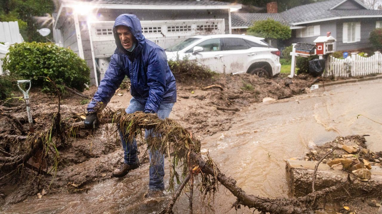 Jeffrey Raines clears debris from a mudslide at his parent's home during a storm on Monday in Los Angeles.