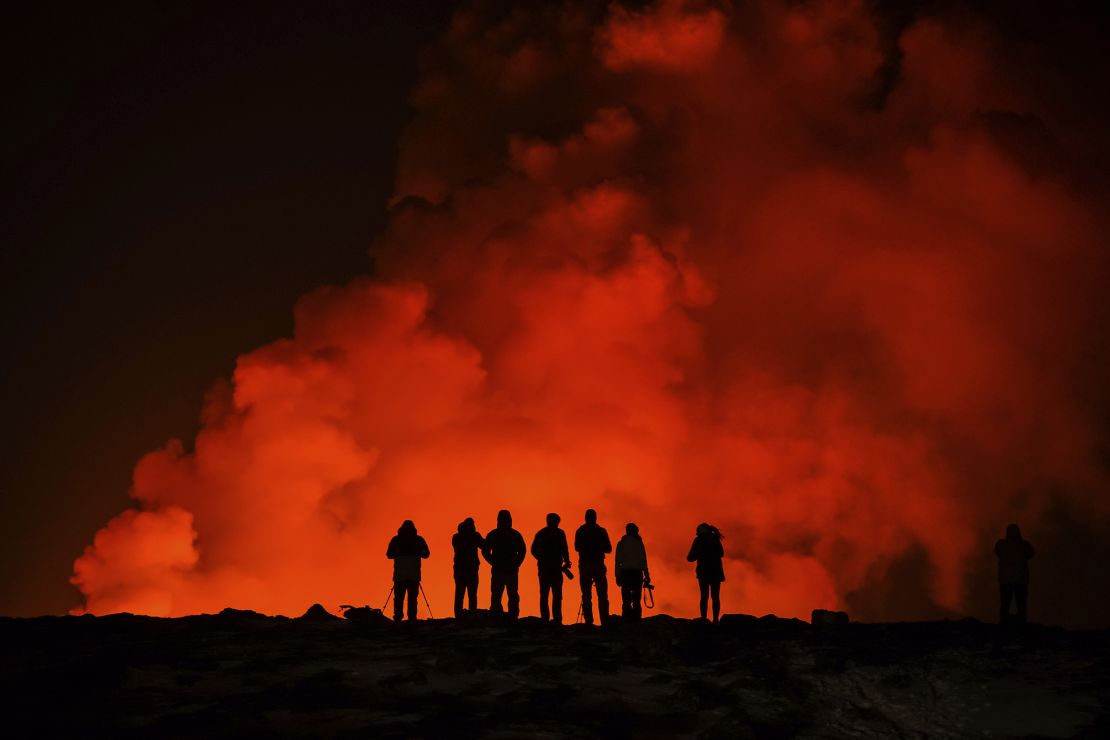 A group of people watch the eruption.