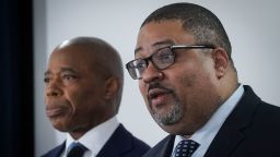Mayor Eric Adams, left, listens as District Attorney Alvin Bragg, right, speaks during a press conference, where several charges for migrants involved in a Times Square brawl with police, Thursday, Feb. 8, 2024, in New York. (AP Photo/Bebeto Matthews)