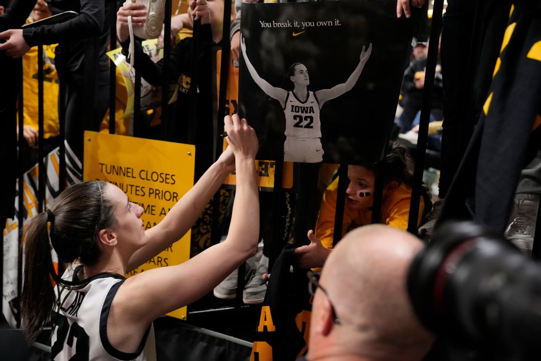 Clark signs an autograph after becoming the all-time NCAA women's college basketball top scorer.