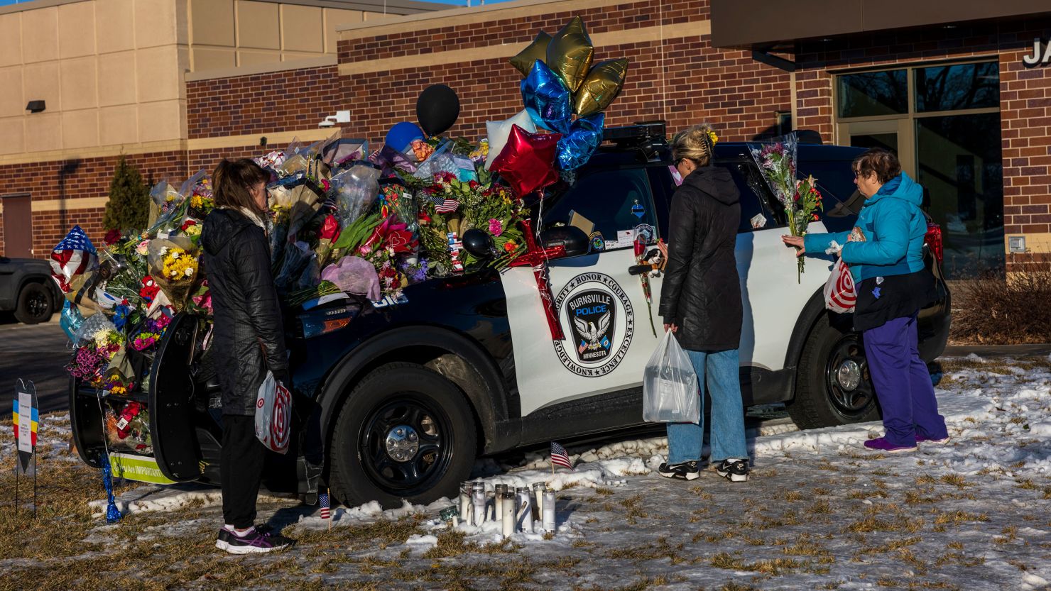 People gather at one of three memorials outside the Burnsville Police Department and City Hall building in Burnsville, Minnesota, on Tuesday.