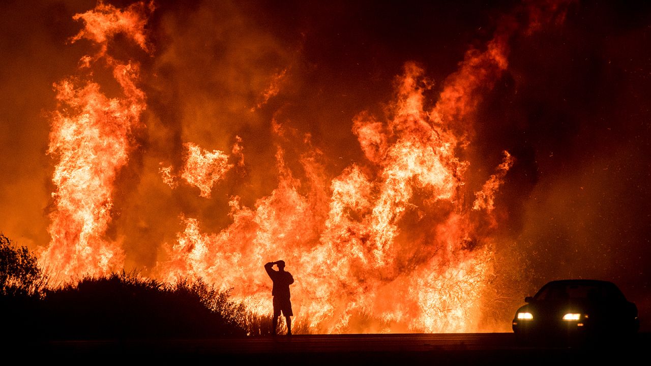 A motorist watches flames from the Thomas Fire leap above a roadway north of Ventura, California, on December 6, 2017.