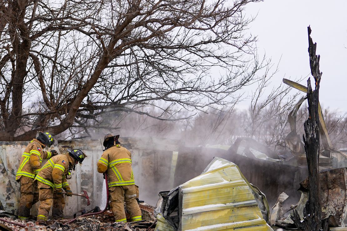 Firefighters from Lubbock, Texas, help put out the smoldering debris of a home destroyed by the Smokehouse Creek Fire on Thursday in Stinnett, Texas.
