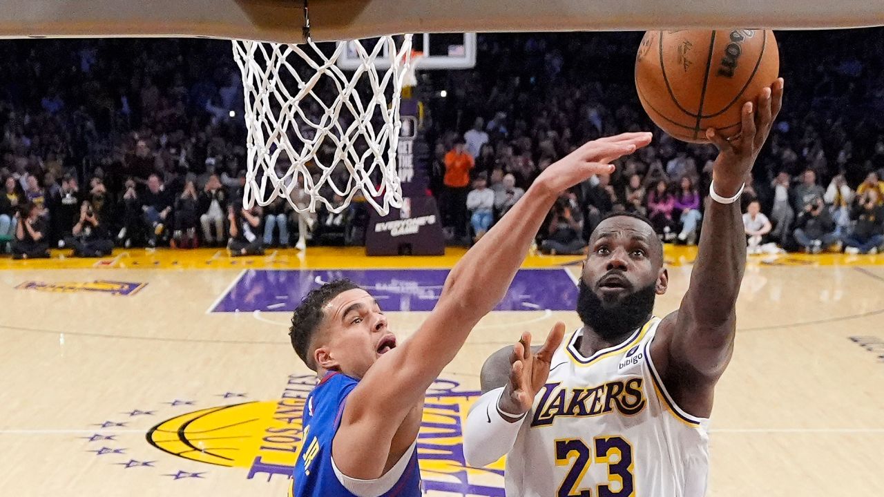 Los Angeles Lakers forward LeBron James, right, scores as Denver Nuggets forward Michael Porter Jr., defends.