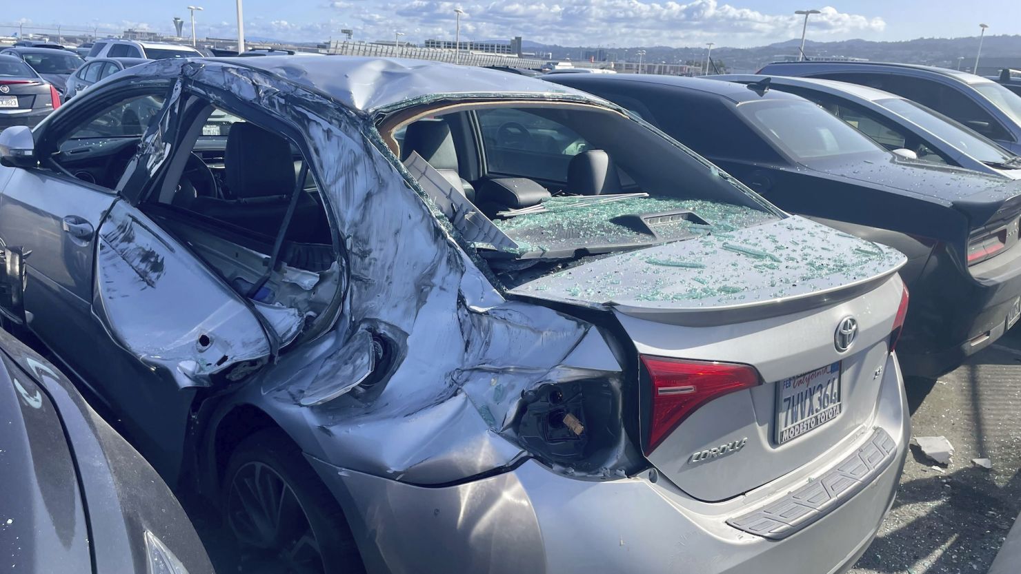 A damaged car is seen Thursday in an employee parking lot after tire debris from a United Airlines plane landed on it at San Francisco International Airport.