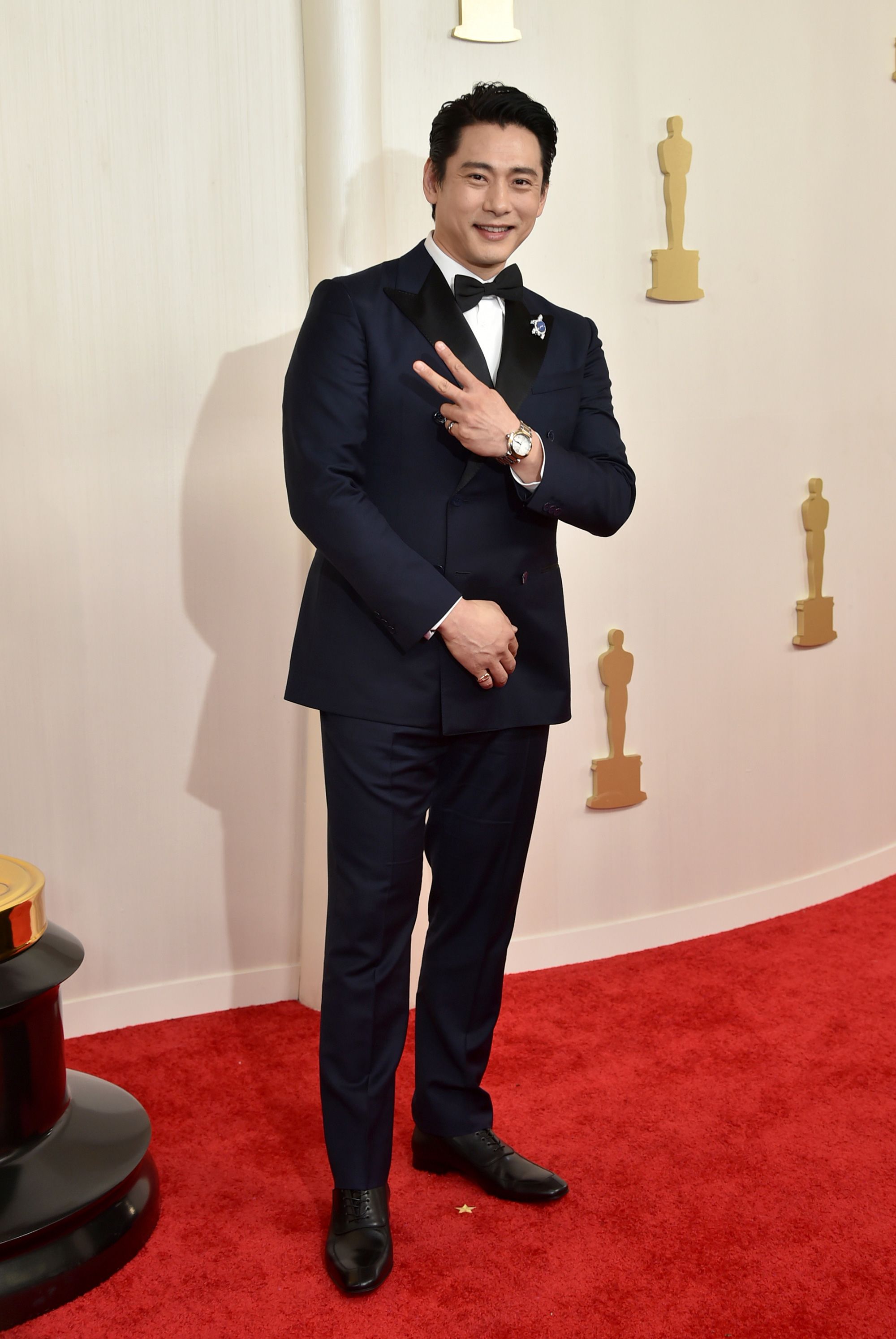 South Korean actor Teo Yoo wore a custom navy double-breasted Louis Vuitton suit. The “Past Lives” star finished off the look with a turtle pin honoring his late pet tortoise Momo, he told Variety on the red carpet.