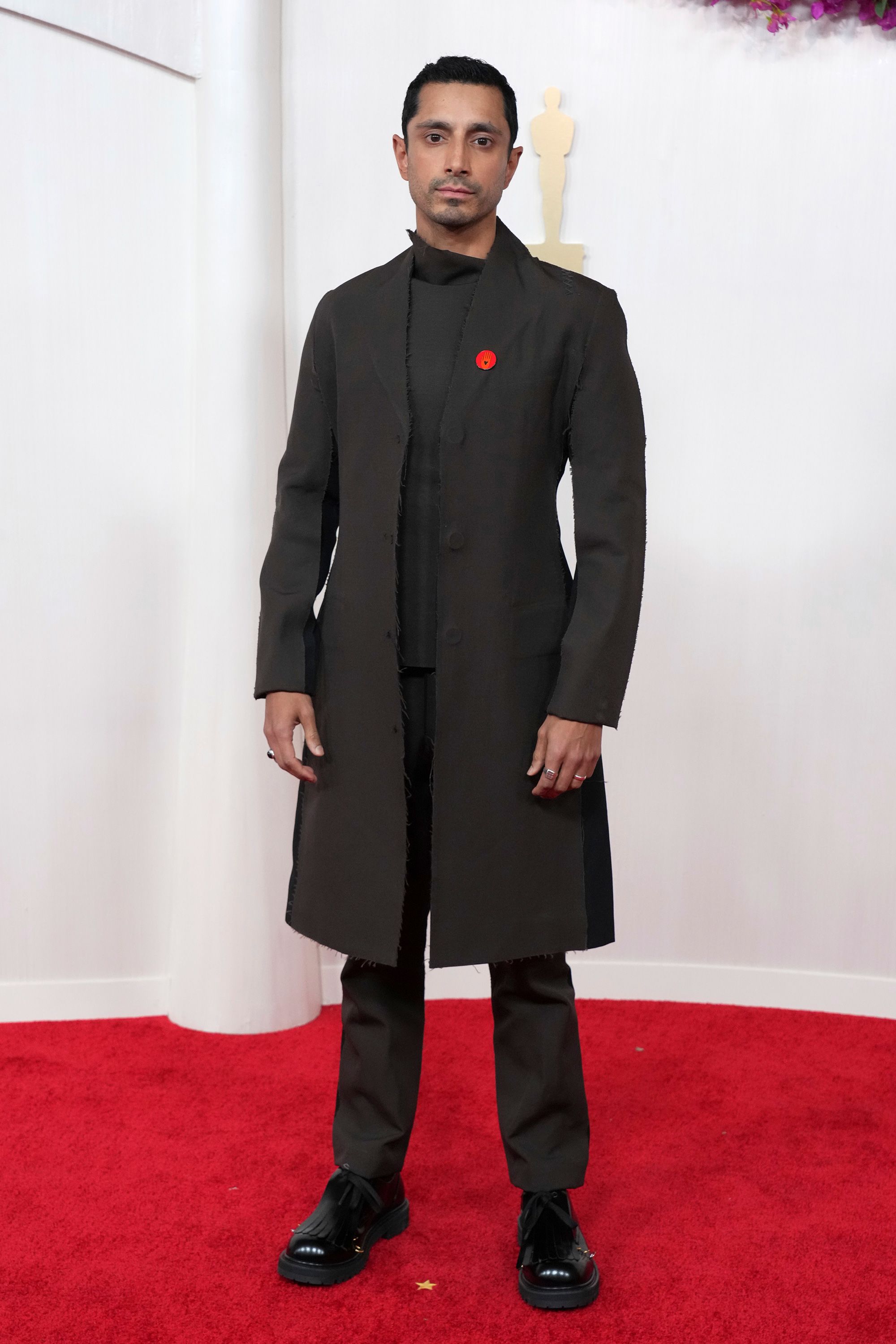 Riz Ahmed arrived in a black ensemble by Marni featuring a knee-length coat.