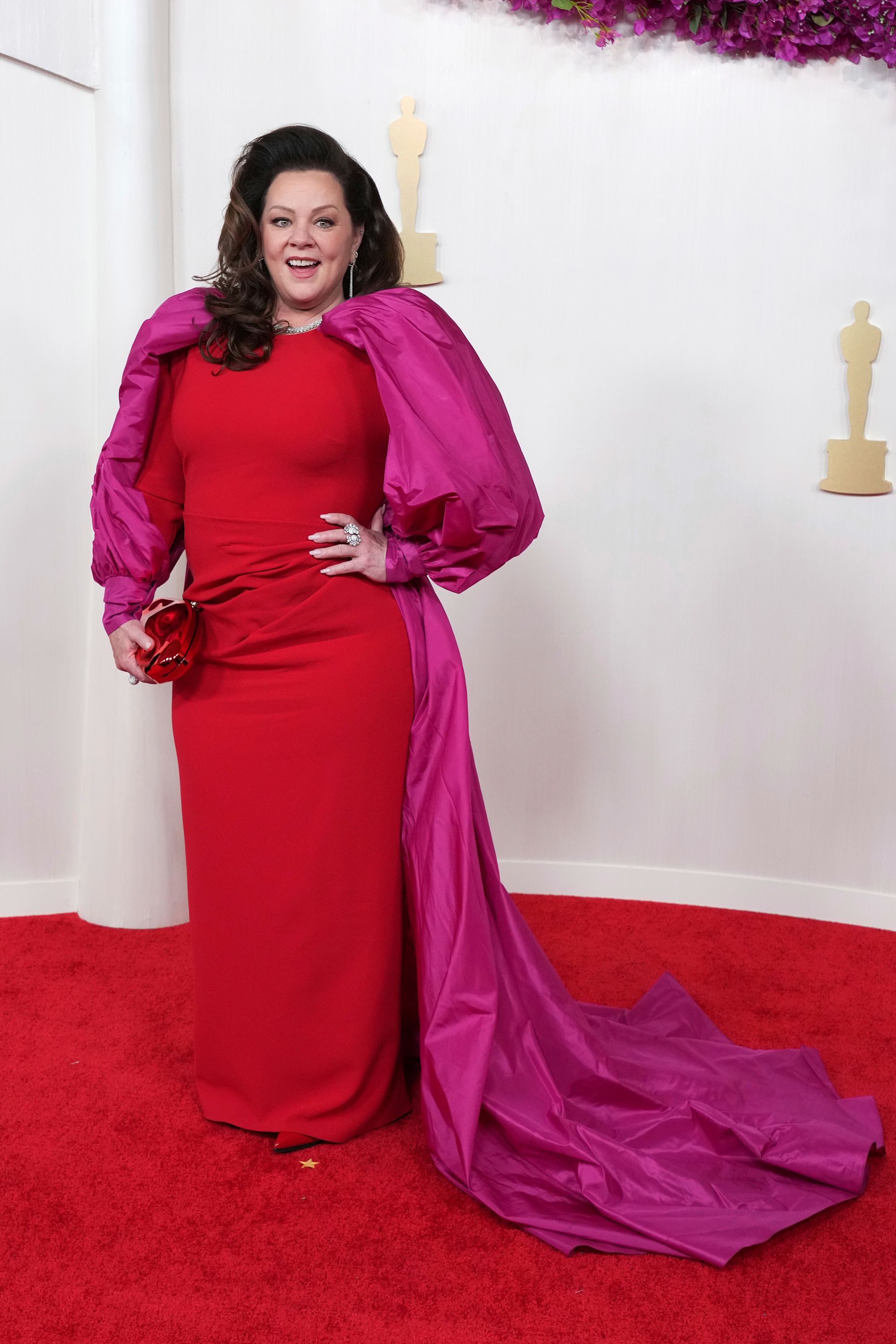 Melissa McCarthy channeled Old Hollywood glamour in a red gown with magenta sleeves. The actor accessorized with Dena Kemp jewelry.