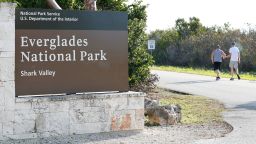 FILE - Visitors walk past a sign for Everglades National Park as they enter from overflow parking, Wednesday, Jan. 2, 2019, in Everglades National Park, Fla.  Officials say a man visiting the Florida Everglades is recovering after being bitten by a crocodile after falling off a boat. The National Park Service says the attack occurred Sunday, March 10, 2024 at the Flamingo Marina in Everglades National Park.  (AP Photo/Wilfredo Lee)
