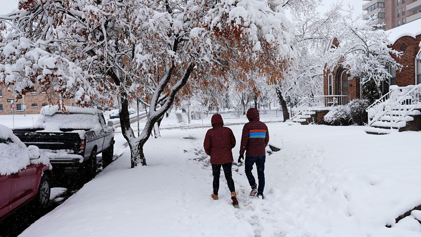 A couple walk along a snowy street in Denver on Thursday, March 14, 2024.