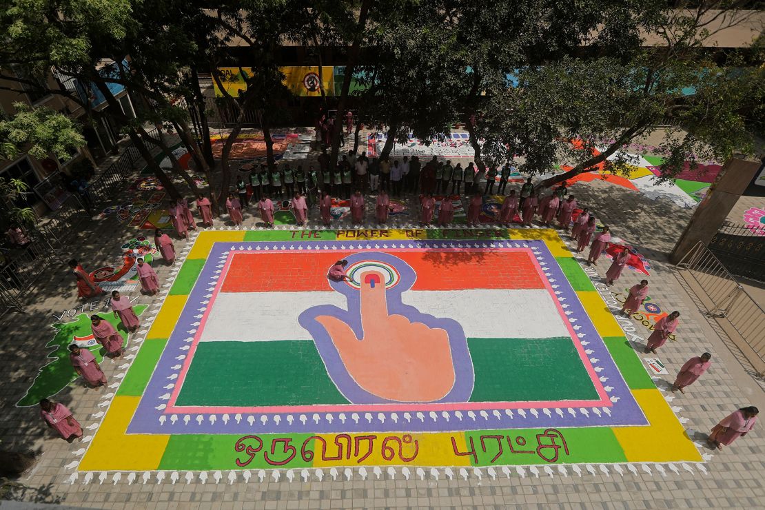 A teacher at a school in Chennai, India, makes final touches to a Rangoli, a traditional artwork made of colored powder, depicting an Indian flag and a woman's finger marked with indelible ink to raise awareness and encourage people to vote in the upcoming general elections.