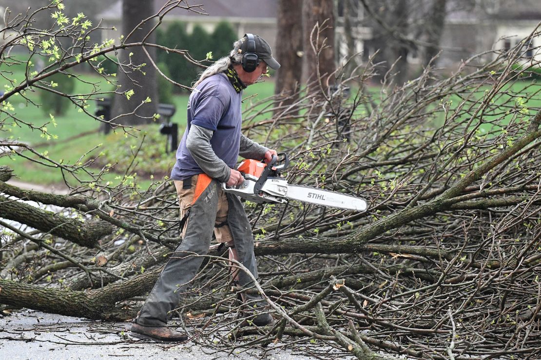A worker cut up downed tress lying across the road following severe storms that passed through Prospect, Kentucky, Tuesday, April 2.