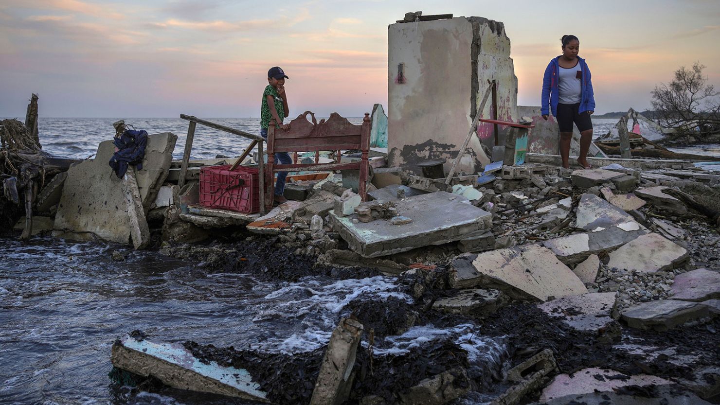 Researchers say individuals will often bear the economic burden of climate change. Yahir Mayoral and Emily Camacho walk amid the rubble of their grandmother's home, destroyed by flooding driven by a sea-level rise in their coastal community of El Bosque, in the state of Tabasco, Mexico, Nov. 30, 2023. (AP Photo/Felix Marquez, File)