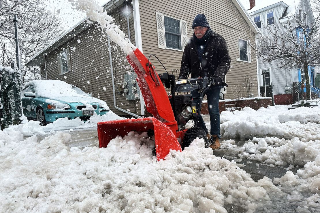 Phil Cloutier removes heavy, wet snow after an early-spring Nor'easter, Thursday, April 4, 2024, in Portland, Maine.