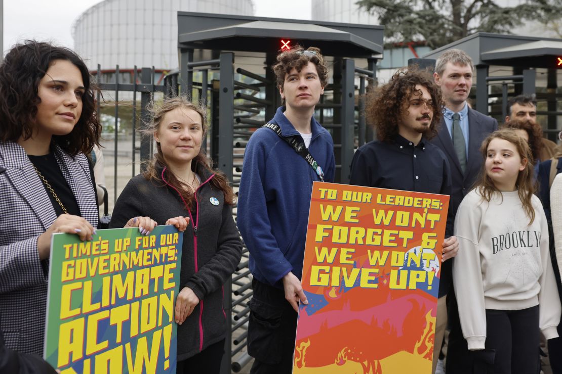 Swedish climate activist Greta Thunberg, second left, joins youths from Portugal during a demonstration outside the European Court of Human Rights Tuesday, April 9, 2024 in Strasbourg, eastern France. Europe's highest human rights court will rule Tuesday on a group of landmark climate change cases aimed at forcing countries to meet international obligations to reduce greenhouse gas emissions. The European Court of Human Rights will hand down decisions in a trio of cases brought by a French mayor, six Portuguese youngsters and more than 2,000 elderly Swiss women who say their governments are not doing enough to combat climate change. (AP Photo/Jean-Francois Badias)