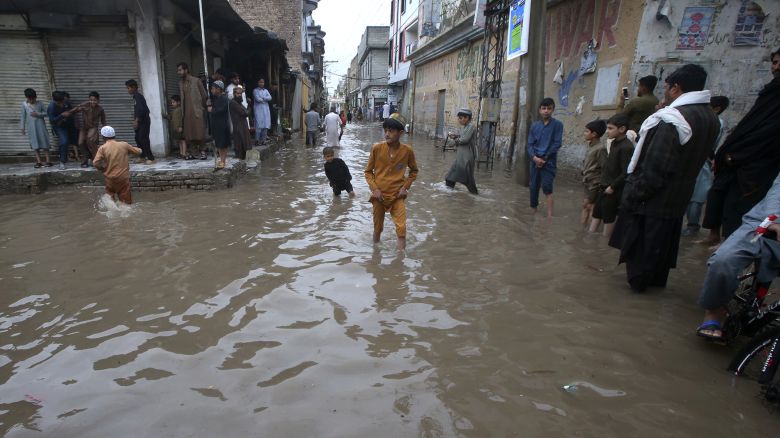 People wade through a flooded street in Peshawar, Pakistan on April 15, 2024.