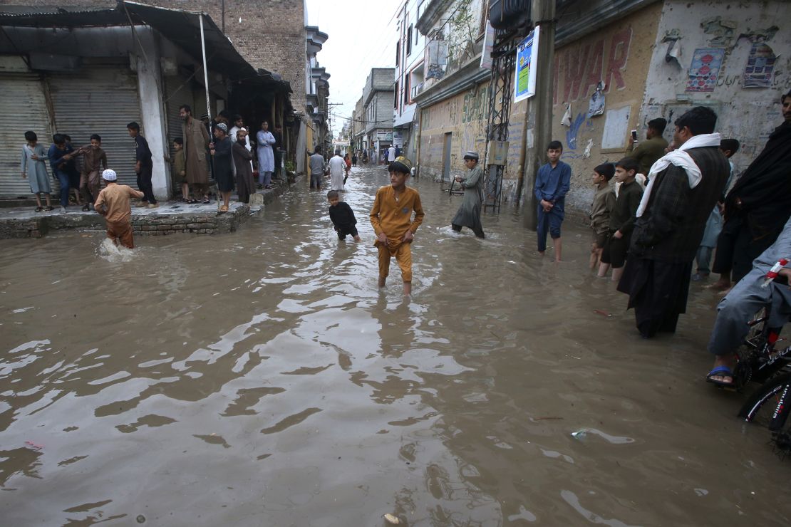 People wade through a street flooded by heavy rain in Peshawar, Pakistan on April 15, 2024.