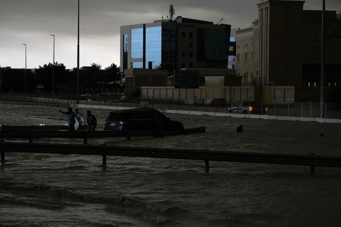 Men gesture as they try to tow a vehicle out of standing water in Dubai, United Arab Emirates, Tuesday.