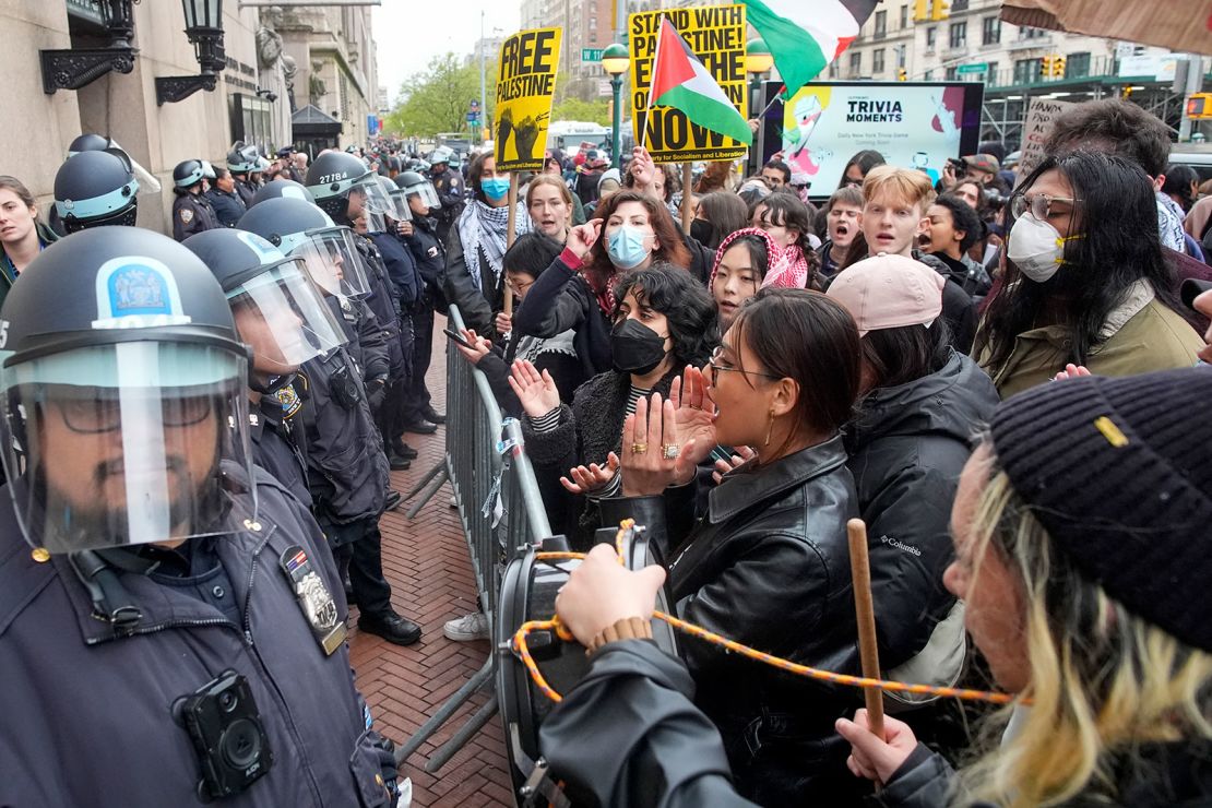 New York City police officers in riot gear stand guard as demonstrators chant slogans outside the Columbia University campus on Thursday in New York.