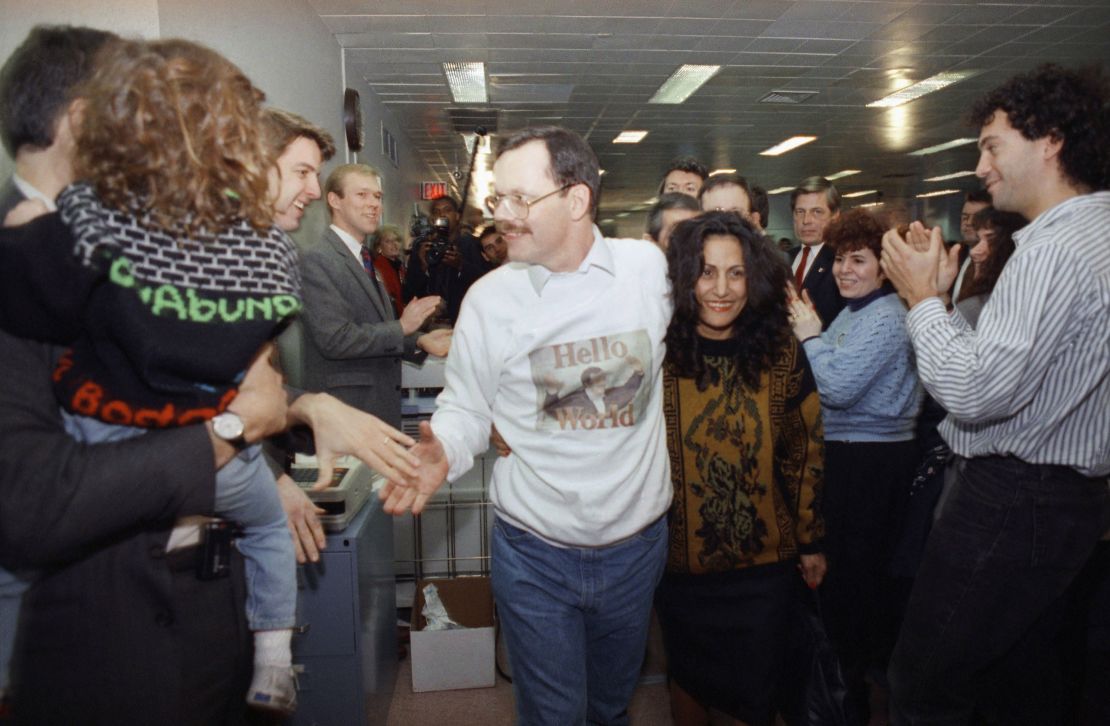 Wearing a sweatshirt printed with his picture, former hostage Terry Anderson greets happy colleagues, on Dec. 10, 1991, at The Associated Press headquarters in New York, as he walks with his arm around fiancee Madeleine Bassil.