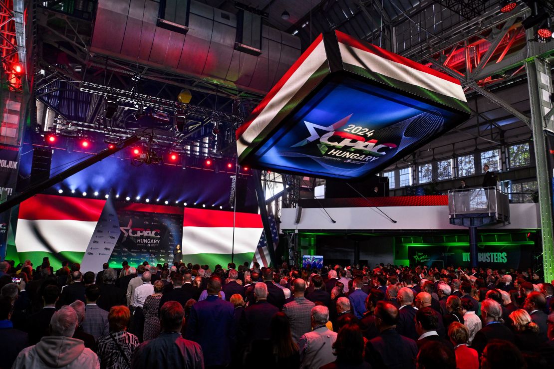 The Hungarian flag is projected on screens over a crowd of people. 