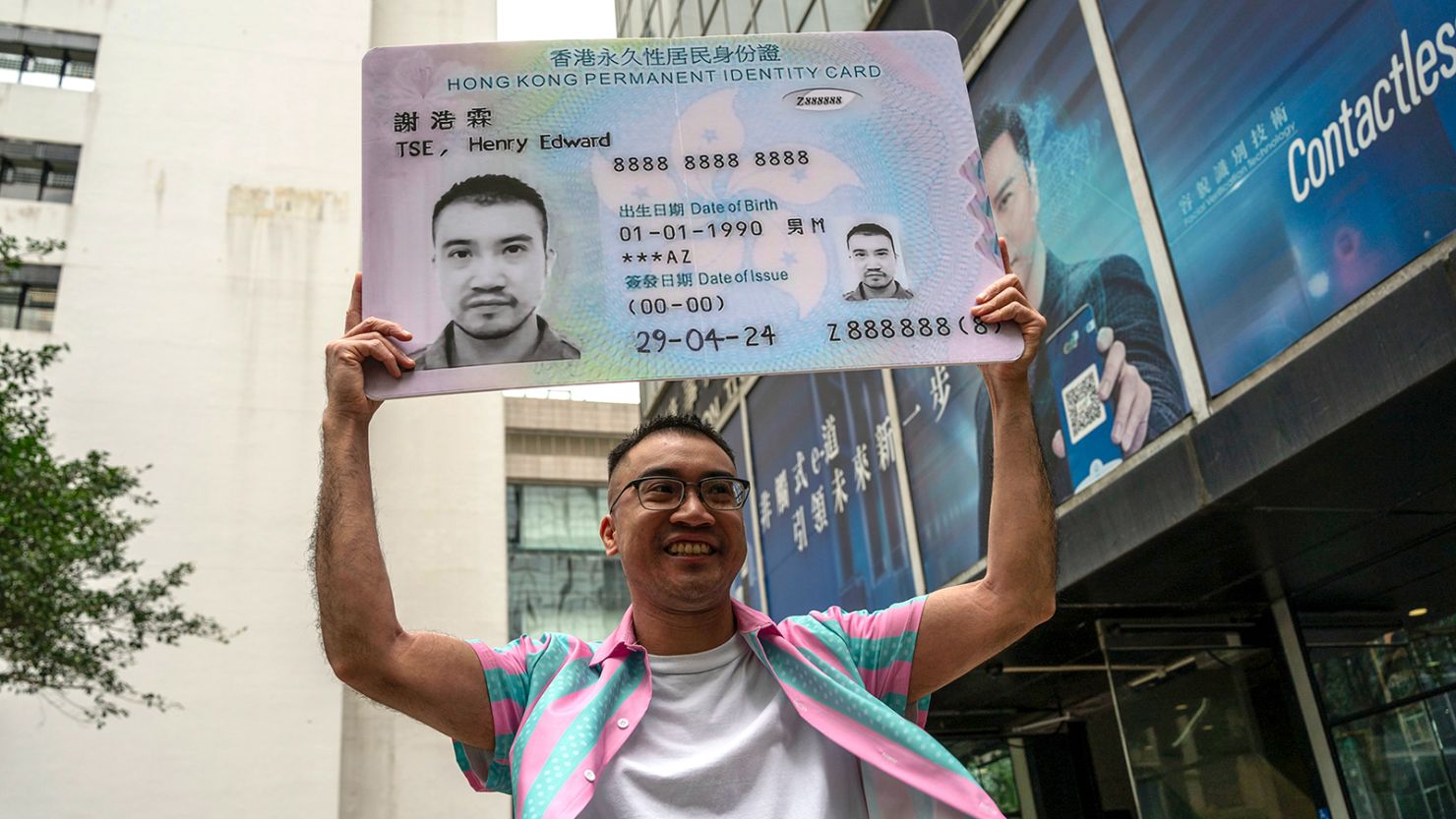 Activist Henry Tse holds up a mock ID card outside the immigration tower in Hong Kong after receiving his new identity document on April 29, 2024.